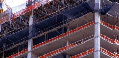 Tall building under construction with guardrails and netting around open floors
