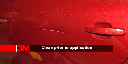 Screenshot of a video showing a scratched door of a red car
