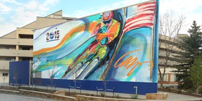 A large outdoor sign featuring a painted image of a bicyclist has bright colors protected by an overlaminate.
