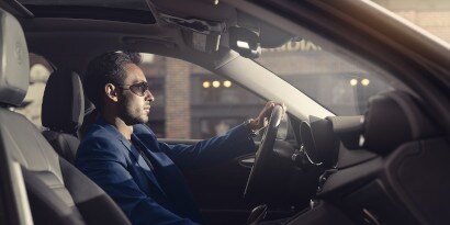 A man inside the car with his left hand holding the steering wheel
