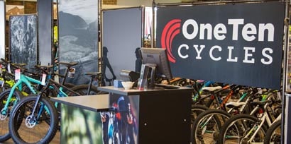 Bikes sitting in front of several pop up displays including a banner that says One Ten Cycles behind a 3M retail signage film wrapped front desk.
