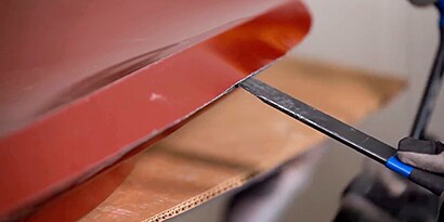 Screenshot of a video showing the separation of door skin to door frame using a thin metal and hammer
