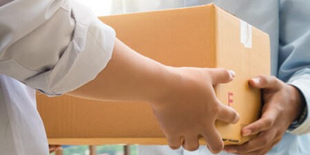 A person handing off a cardboard box to another person.
