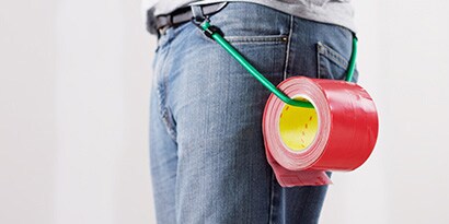 Tape hanging from a bungee at the waist of a contractor, showing portability.
